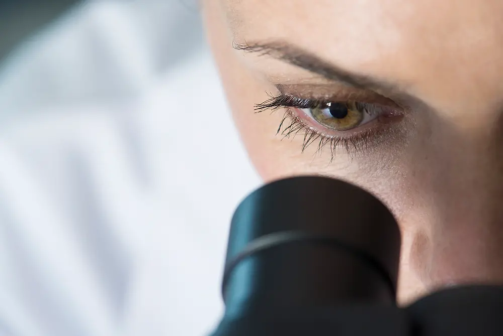 Ojo de una mujer mirando al microscopio.