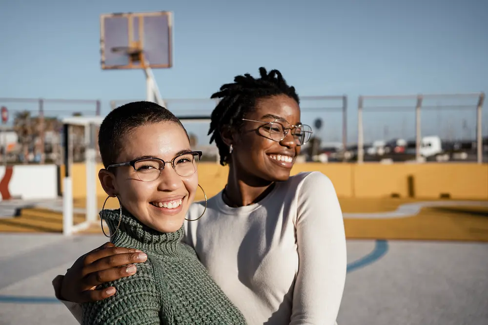 Dos mujeres que se abrazan en una cancha de basket. 